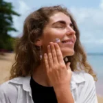 Woman applying Sun Screen at the beach during summer to protect and hydrate skin